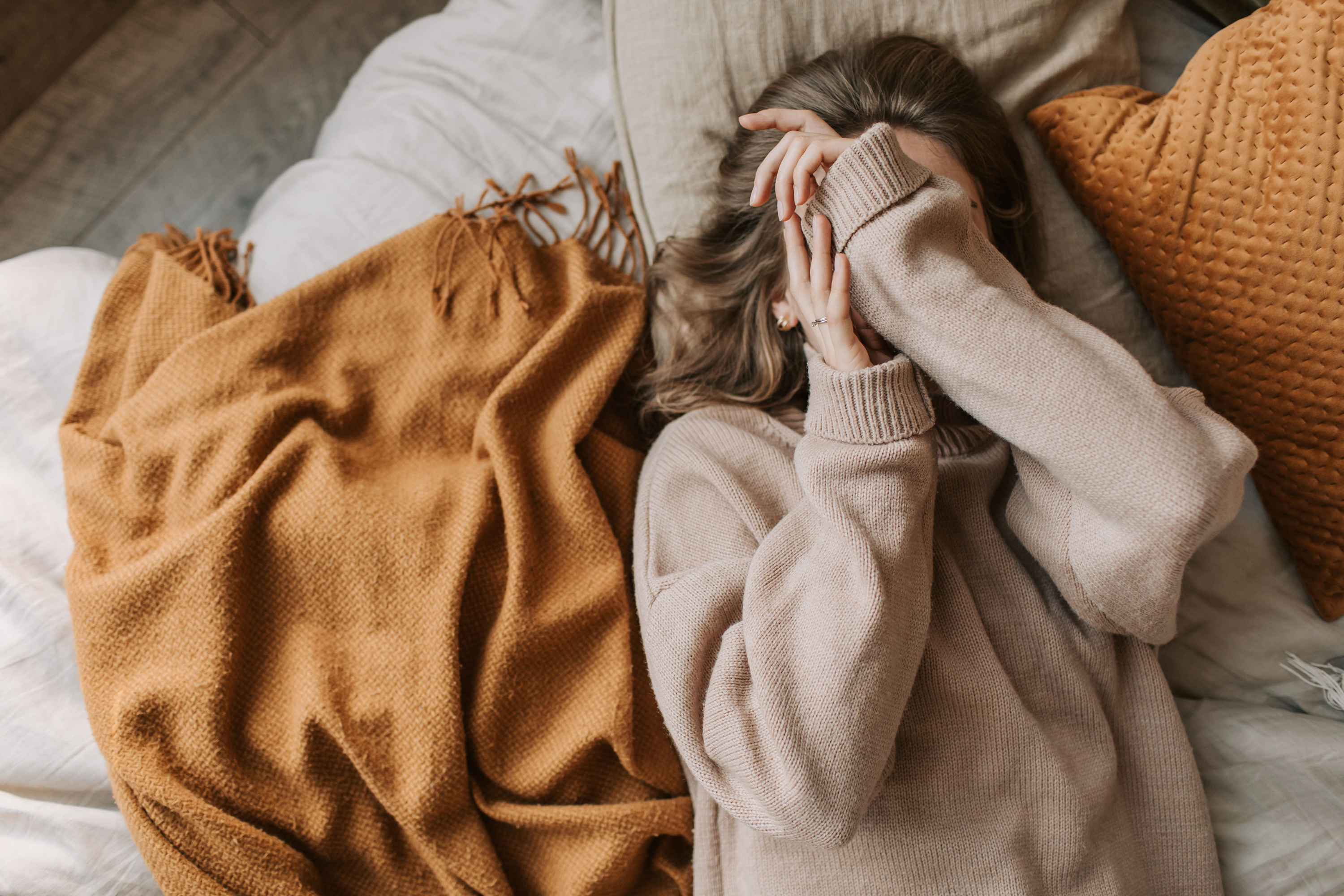 Woman relaxing comfortably on bed in cozy sweater practicing mindfulness and body awareness