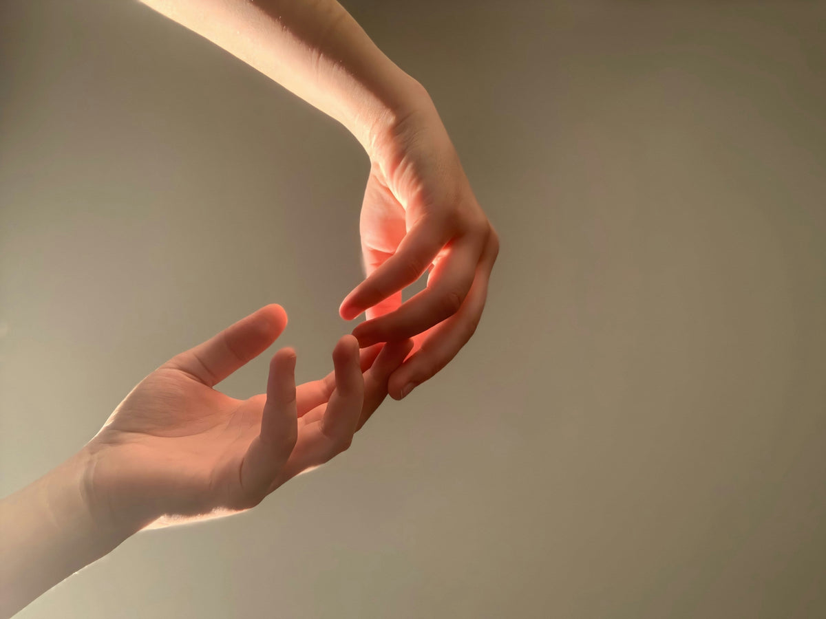 Two hands reaching towards each other in warm, soft lighting