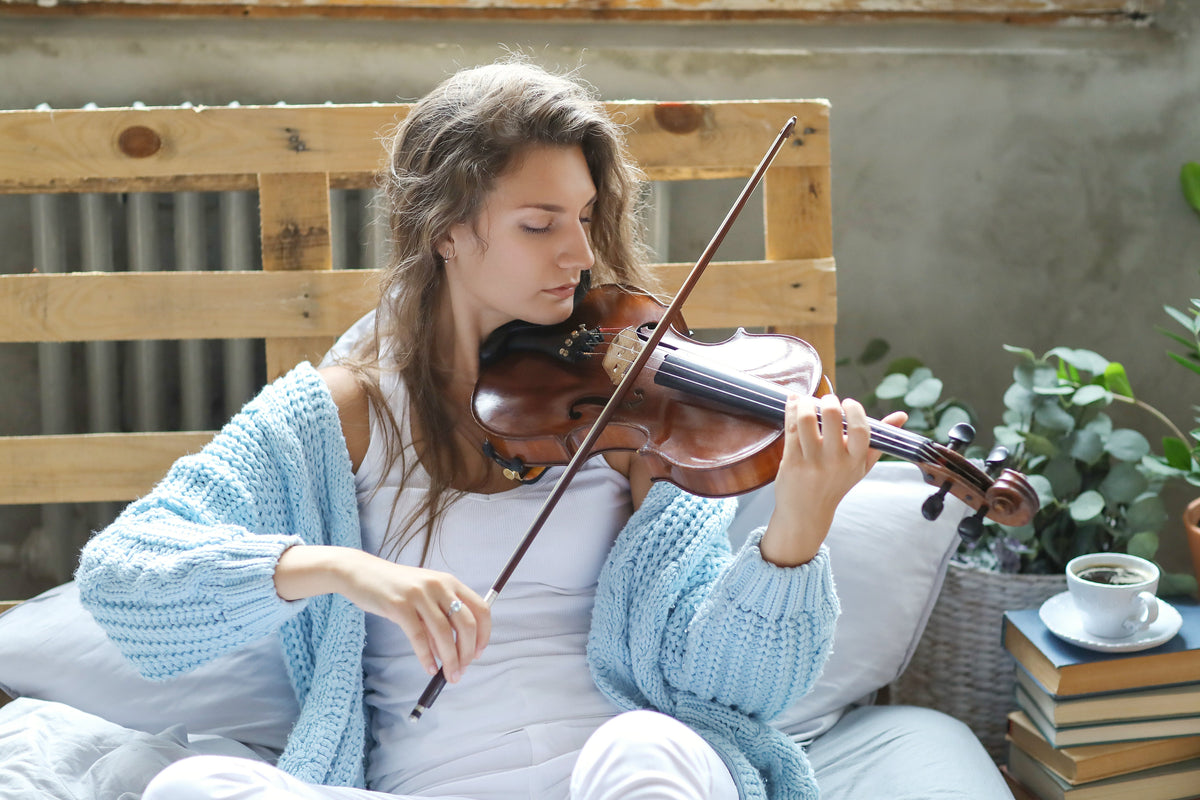 Woman playing the violin in bed