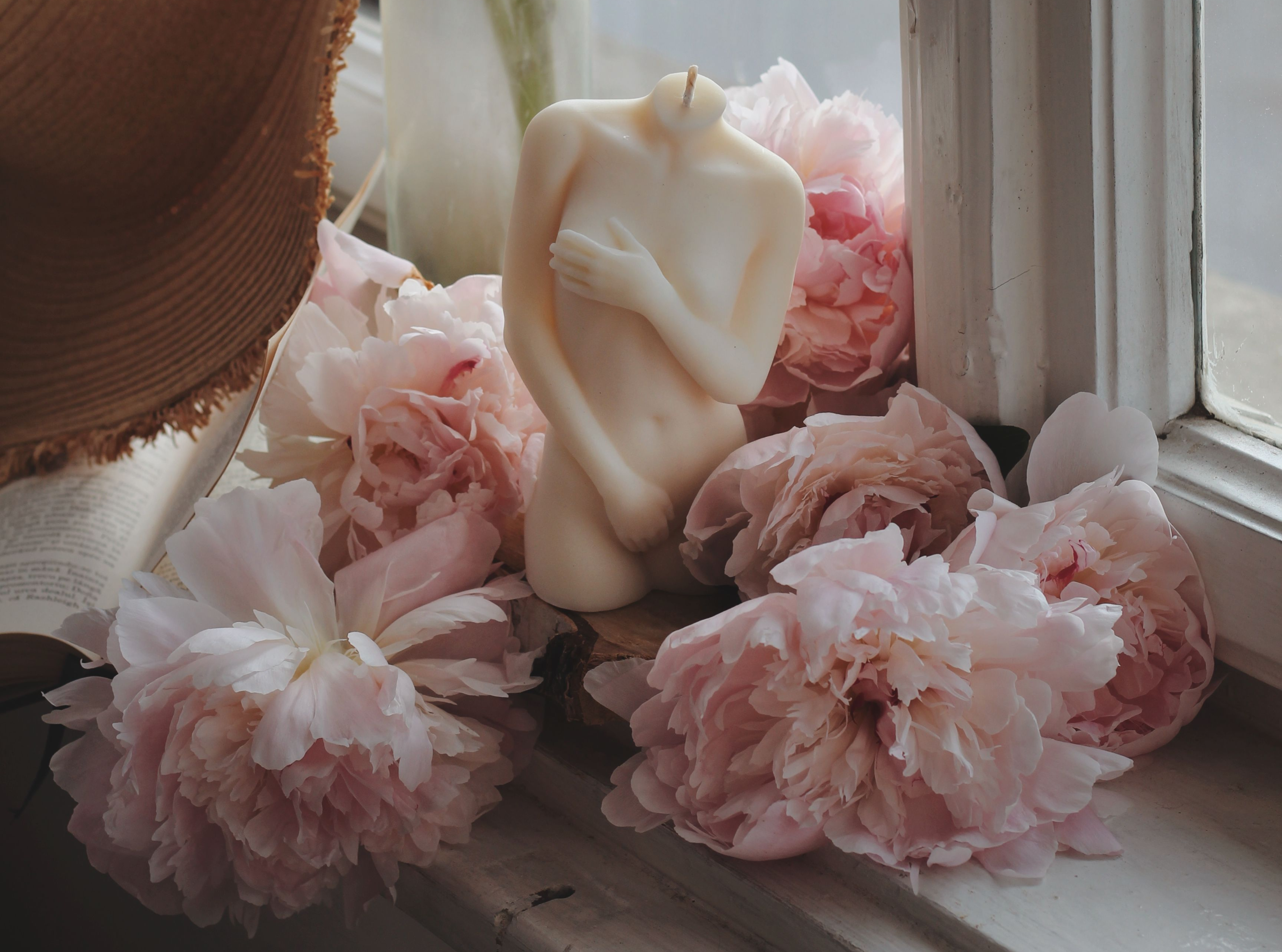 Artistic female body candle surrounded by pink peonies, symbolizing the G-Spot complex and sexual wellness guide