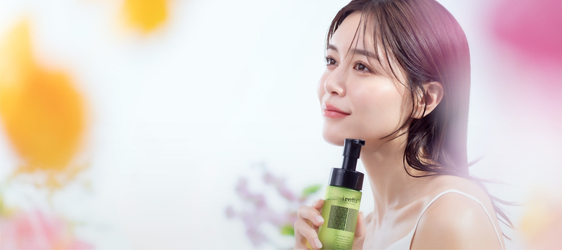 Woman holding a iroha intimate care bottle with colorful blurred background